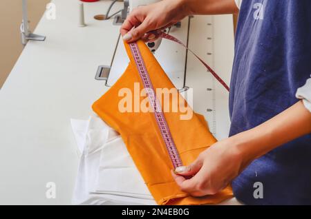 Dressmaker measures the cloth for sewing clothes with measuring tape Stock Photo