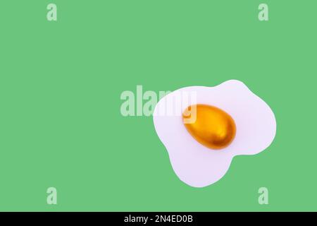 Creative layout made of scrambled eggs with decorated golden Easter eggs on a green background. Minimal Spring holidays concept. Stock Photo