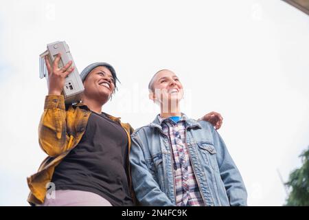 Two young urban stylish women listening to music from the boombox and making rap rhymes. Concept: Lifestyle, urban music, singing Stock Photo