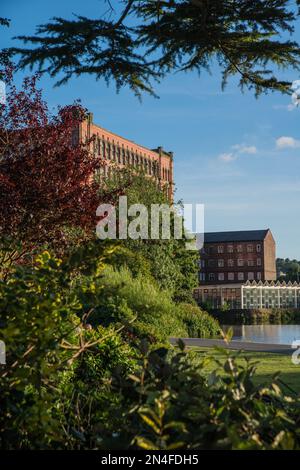 East Mill, peeping from the trees and the smaller North Mill, historical cotton spinning mills in Belper, Derbyshire, England Stock Photo