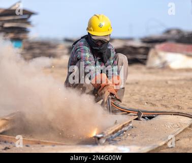 Gadani Pakistan August 2021, a worker wearing safety helmet cutting metal sheet with welding arc, labors working at ship bfreaking yard, labor day Pak Stock Photo