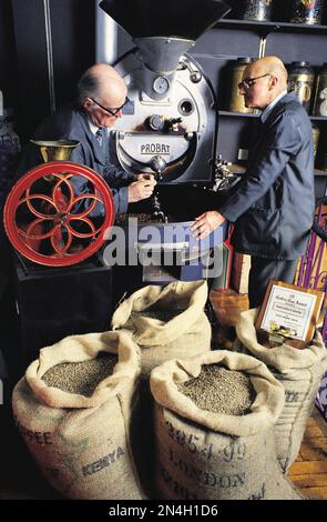United Kingdom. England. Two men checking Kenyan coffee beans being roasted. Stock Photo