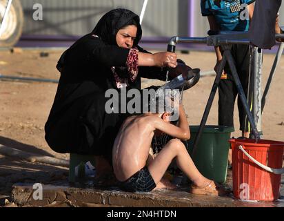 An Iraqi refugee woman, left, washes her son at a camp for displaced Iraqis who fled from Mosul and other towns, in Khazer area outside Irbil, northern Iraq, Sunday, June 22, 2014. Sunni militants on Sunday captured two border crossings, one along the frontier with Jordan and the other with Syria, security and military officials said, as they pressed on with their offensive in one of Iraq's most restive regions. (AP Photo/Hussein Malla)