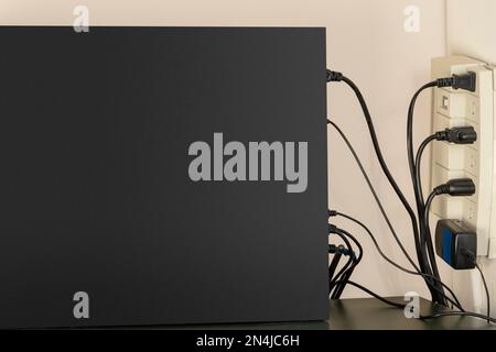 Side view of desktop computer and power hookup to wall.  Black side of tower case excellent for reverse text. Stock Photo