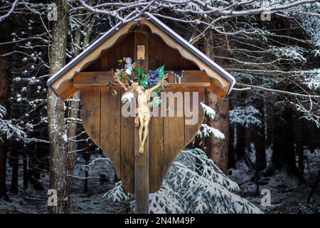 A closeup shot of a crucifix on a wooden sign in winter Stock Photo