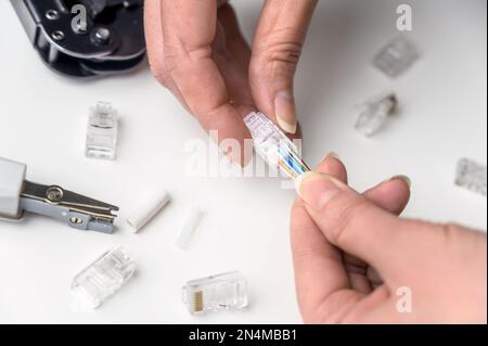 A woman's hand inserts an internet cable into a clamp connector. utp ethernet network cable plug. The concept of internet communications. Stock Photo