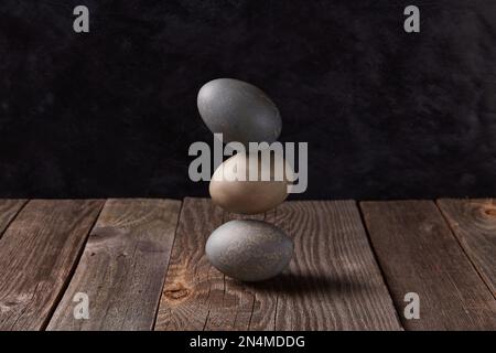 Balancing dyed eggs on wooden table. Easter celebration concept Stock Photo