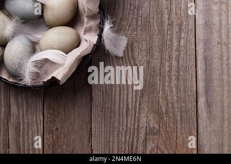 Eggs and feathers on rustic wooden table. Easter celebration concept Stock Photo