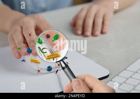 Woman with magnifying glass detecting microbes on computer mouse, closeup Stock Photo