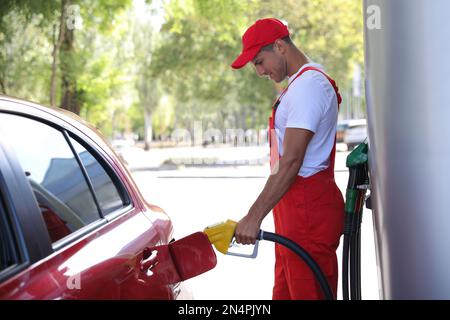 Worker refueling car at modern gas station Stock Photo