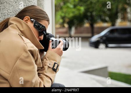 Private detective with modern camera spying on city street Stock Photo