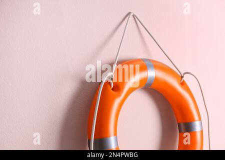 Orange lifebuoy and space for text on pink background. Rescue equipment Stock Photo