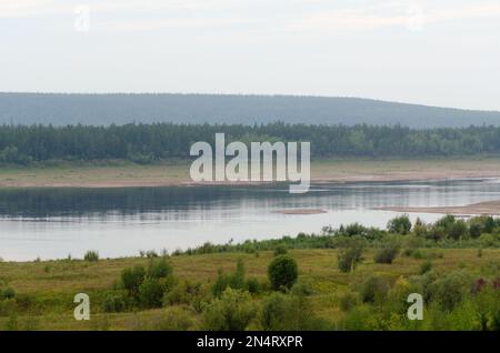 Wild Northern Yakut river Vilyui in Russia, flows through the tundra with overgrown banks on the background of spruce forests of the taiga summer day. Stock Photo