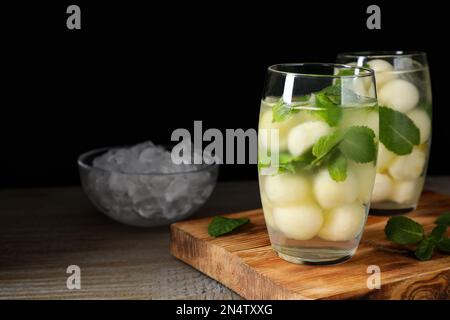 Tasty melon ball drink on wooden table against black background. Space for text Stock Photo