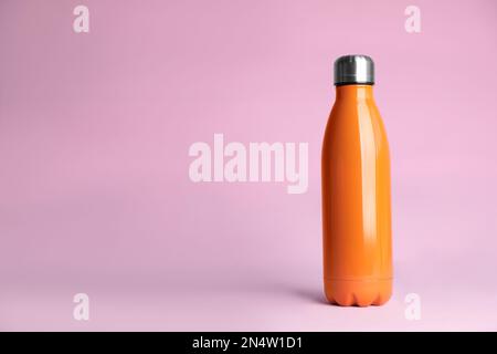 Stylish thermo bottle on pink background, space for text Stock Photo