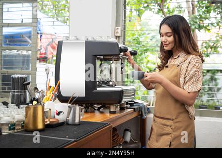 Asian woman barista making coffee by machine in the cafe Stock Photo