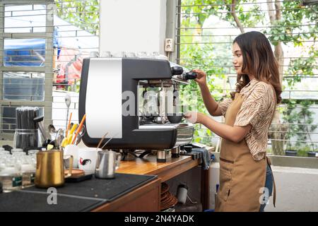 Asian woman barista making coffee by machine in the cafe Stock Photo