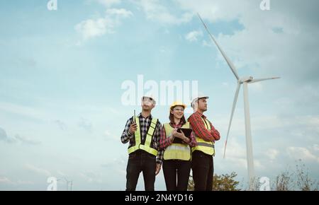 Portrait of a group of happy engineers looking in an agricultural field with wind turbines. Renewable and clean energy concept. Stock Photo