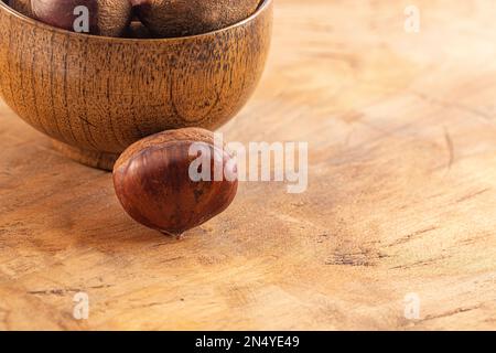 Bowl of Raw and Whole Chestnuts on a Wooden Table Stock Photo