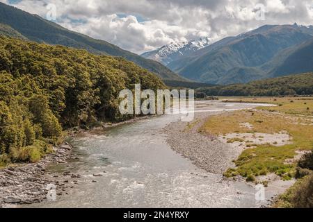 The Makarora river in the Otago region of New Zealand flowing towards Wanaka Lake with snow capped mountains in the distance Stock Photo