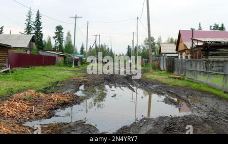 A large puddle of mud on a residential street in the Northern Yakut village in the forest. Stock Photo