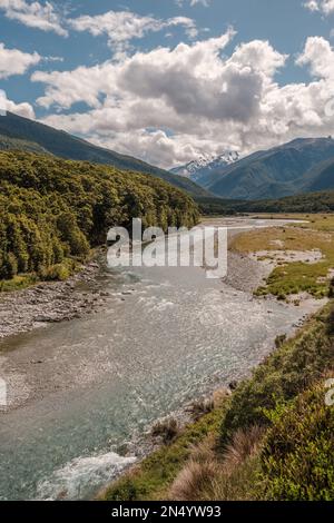 The Makarora river in the Otago region of New Zealand flowing towards Wanaka Lake with snow capped mountains in the distance Stock Photo