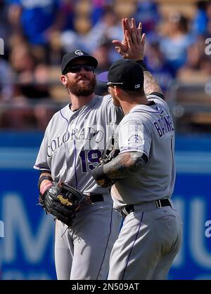 Colorado Rockies' Charlie Blackmon, left, shows to trainer Scott Gehret  where a foul ball hit his batting helmet as he stood in the on-deck circle,  during the third inning of the team's