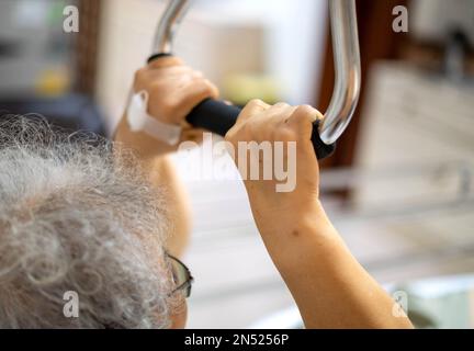 Older handicapped woman using resistance stretch band exercise for patient on a bed at the ward hospital. Stock Photo