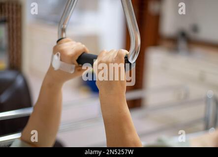 Older handicapped woman using resistance stretch band exercise for patient on a bed at the ward hospital. Stock Photo