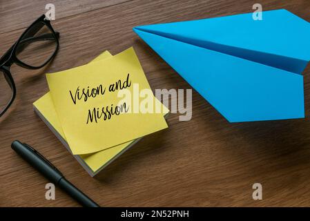 Selective focus of glasses, pen, paper plane and yellow memo note written with Vision and mission. Stock Photo