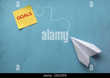 Concept of paper plane flying towards goals on blue background. Stock Photo