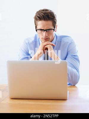 Hard at work. A handsome young businessman focused on his laptop. Stock Photo