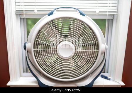 used dirty window fan dusty white round fan in window cool off Stock Photo