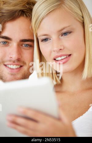 This is so easy to use. Closeup of a happy young couple using a tablet together. Stock Photo