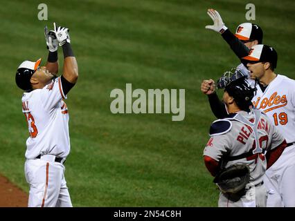 Baltimore Orioles' Nelson Cruz, left, celebrates with teammates J.J. Hardy  (2) and David Lough after Hardy and Lough scored on a double by Jimmy  Paredes in the 11th inning in the first