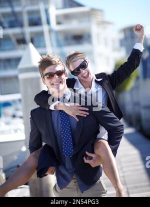 Making corporate life interesting. Young business couple celebrating their success at the marina. Stock Photo