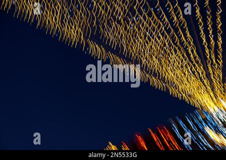 Abstraction blurred movement lights garlands. Golden lights of a blurred garland on the background of a purple blue sky. The concept of a night Stock Photo