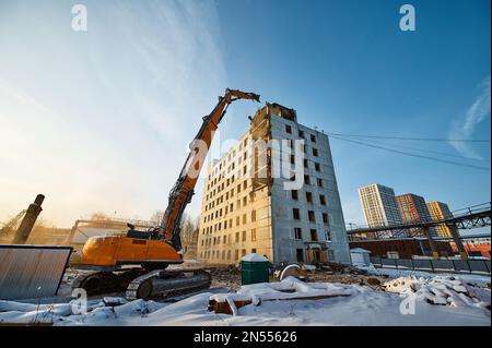 Dismantling of old highrise building with crawler excavator Stock Photo