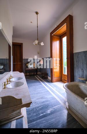 An upstairs, large bathroom with big bathtub and double sinks, marble flooring. At the mansion museum, Museo Pignatelli in Naples, Napoli, Italy, Ital Stock Photo