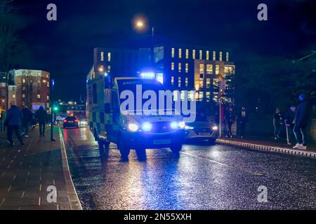An ambulance on the road, with blue emergency lights flashing, in the city at night. Stock Photo