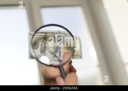 Counterfeiter forges banknotes. Fake concept. Fake money American dollars, magnifier. view money under a magnifying glass. watermark, water mark Stock Photo