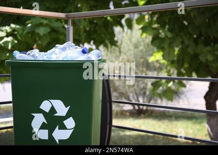 Many used plastic bottles in trash bin outdoors. Recycling problem Stock Photo