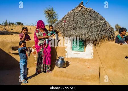 Colourfully dressed desert dwellers, mud hut settlement in the Thar