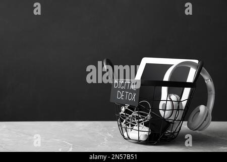 Trash bin with different gadgets and words DIGITAL DETOX on light grey marble table. Space for text Stock Photo