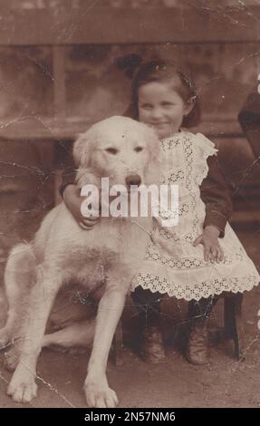 Vintage Photograph of a  young Girl and her pet Dog / hand holding puppy / hugging dogs / Dog Hugs / big white dog / protector dog / Holding dog under arm Stock Photo