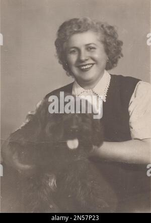 Vintage Photograph of Lady and her pet dog / hand holding puppy / hugging dogs , Dog Hugs / vintage laughing / smilling lady / happy lady / Holding dog under arm Stock Photo