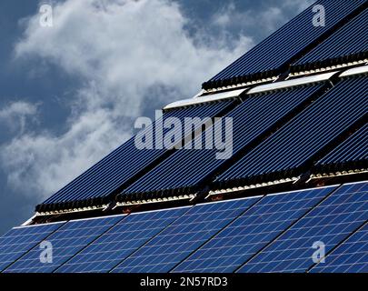 combination roof installed photovoltaic PV solar panels and solar water heater pipe system on brown sloped clay roof. sun collector water pipe heaters Stock Photo