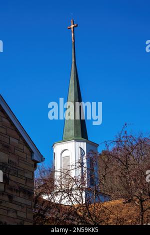 St. Joseph's Catholic Church steeple with a Pax Christi symbol on it and a cross at the top on a spring day in Taylors Falls, Minnesota USA. Stock Photo