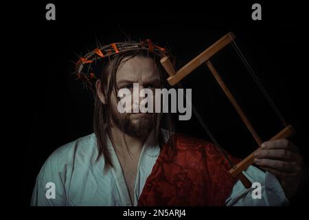 Jesus in robe, red sash and crown of thorns holding rosary and standing  with open arms against blue Stock Photo by LightFieldStudios