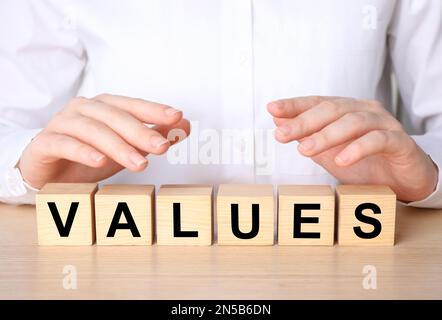 Core values concept. Woman with cubes at wooden table, closeup Stock Photo